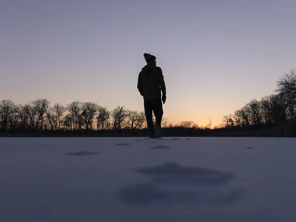 Ben silhouetted on a snowy lake at dusk